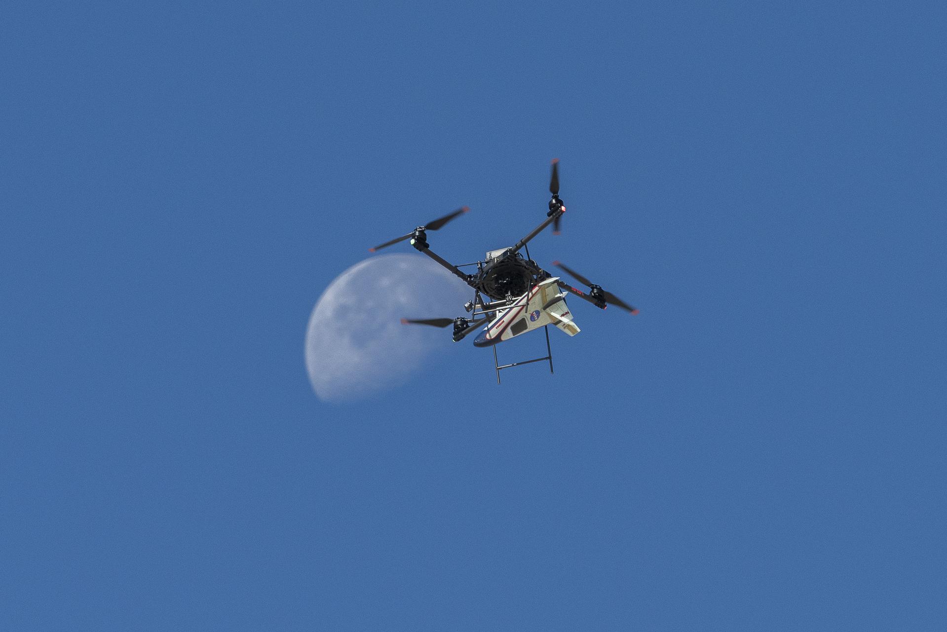 An atmospheric probe model carried by a quad rotor aircraft rises and the Moon is visible.