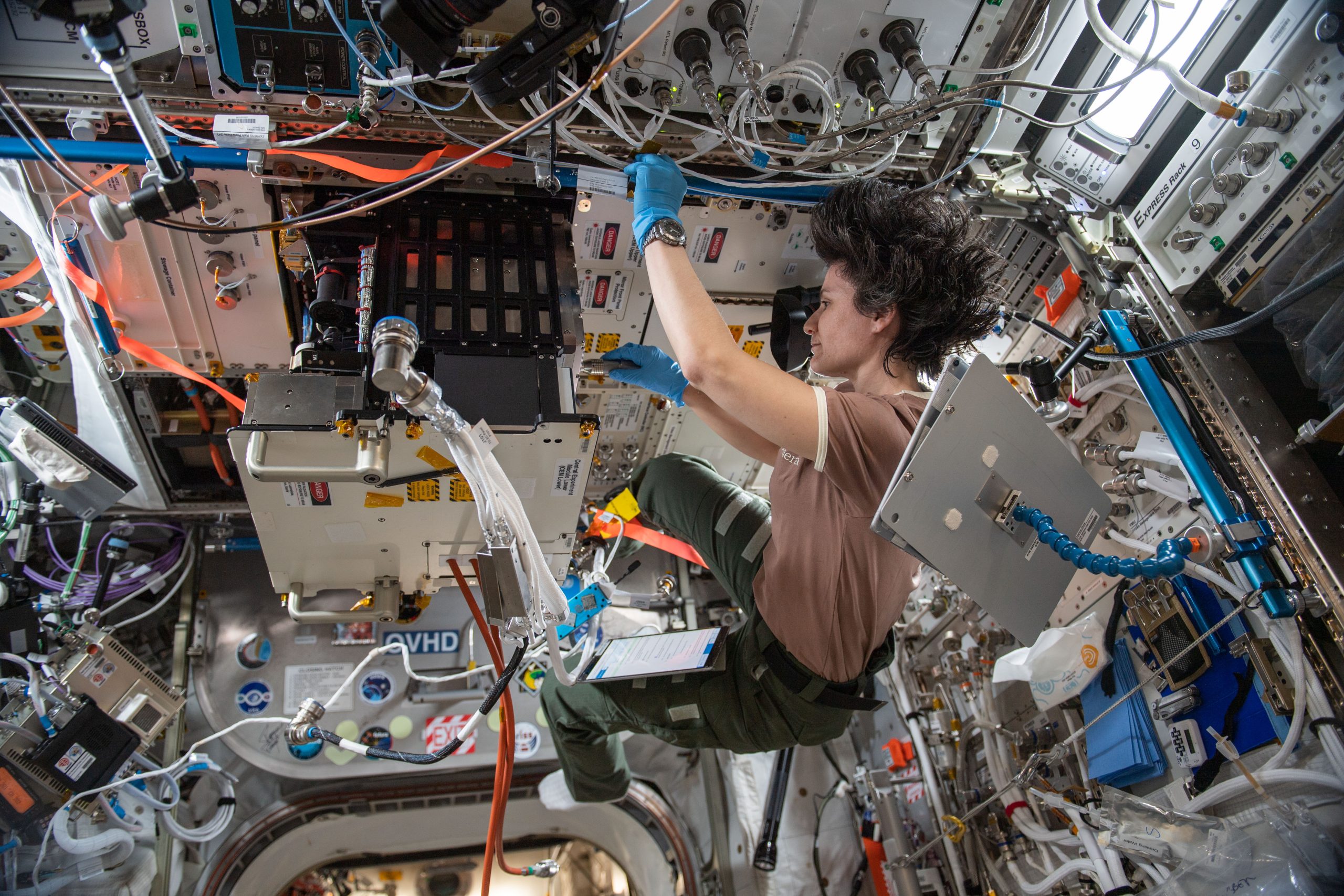An astronaut floats aboard the International Space Station while conducting an experiment.