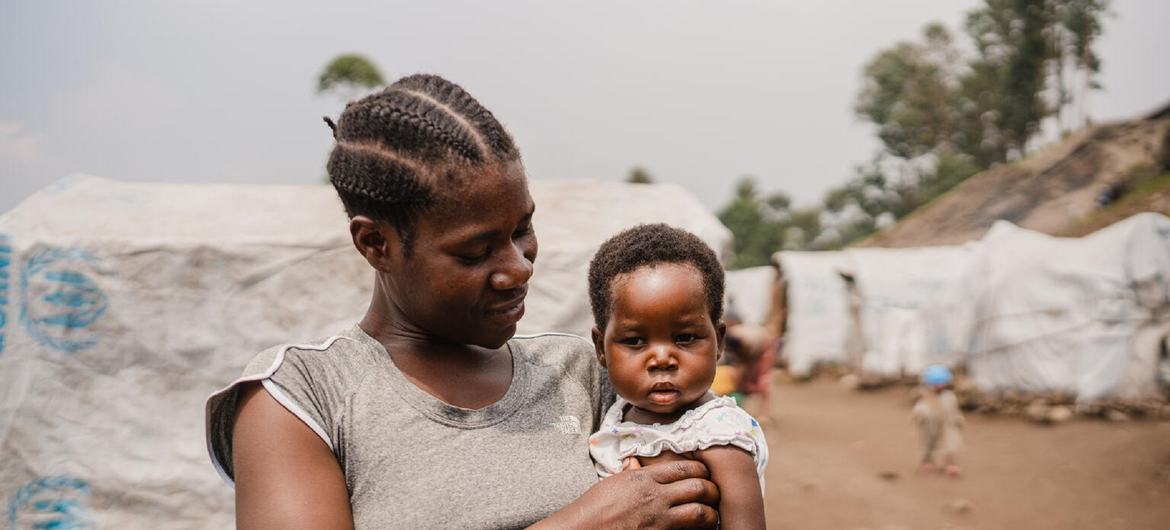 A mother holds her young child after having visited a UN-supported medical clinic at an IDP camp in North Kivu.