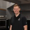 Image shows man smiling in black shirt with NASA's Artemis logo.