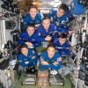 The seven-member Expedition 73 crew poses for a portrait inside the International Space Station's Zvezda service module.