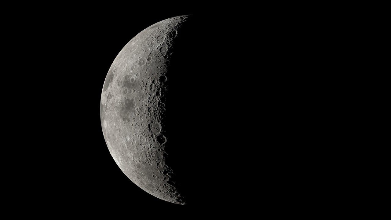A large sphere is prominent in the center of the image. It is pockmarked with indentations and is generally grey, with patches of dark.