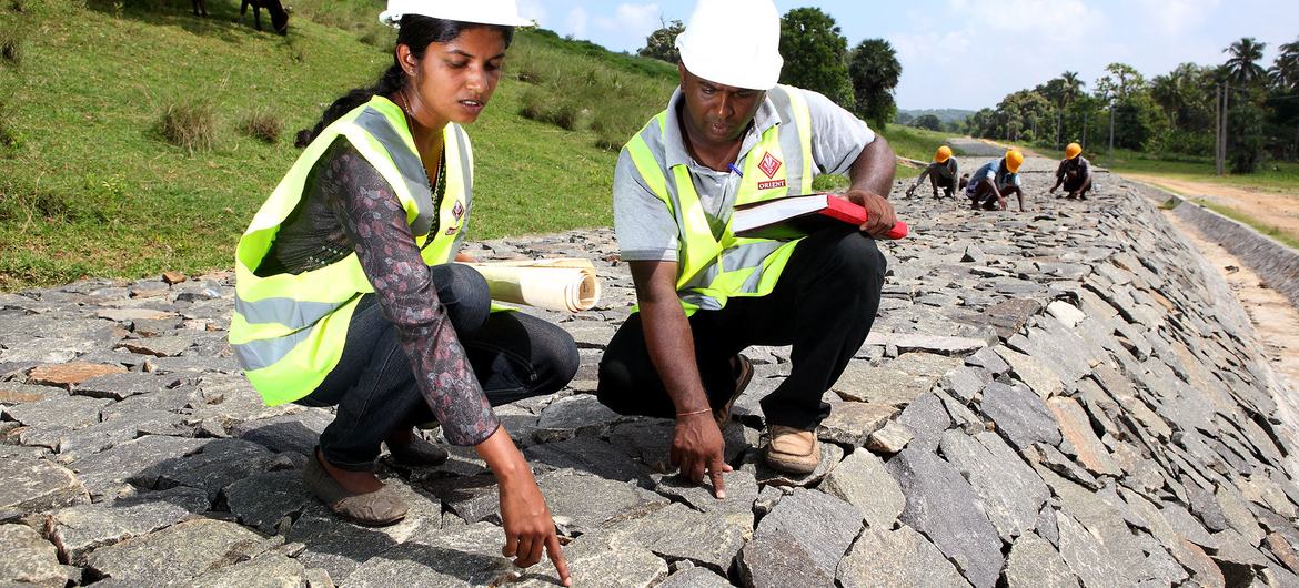 Working alongside her male team member, a woman employee checks the quality of work at a dam under construction in Sri Lanka. Working alongside her male team member, a woman employee checks the quality of work at a dam under construction in Sri Lanka.