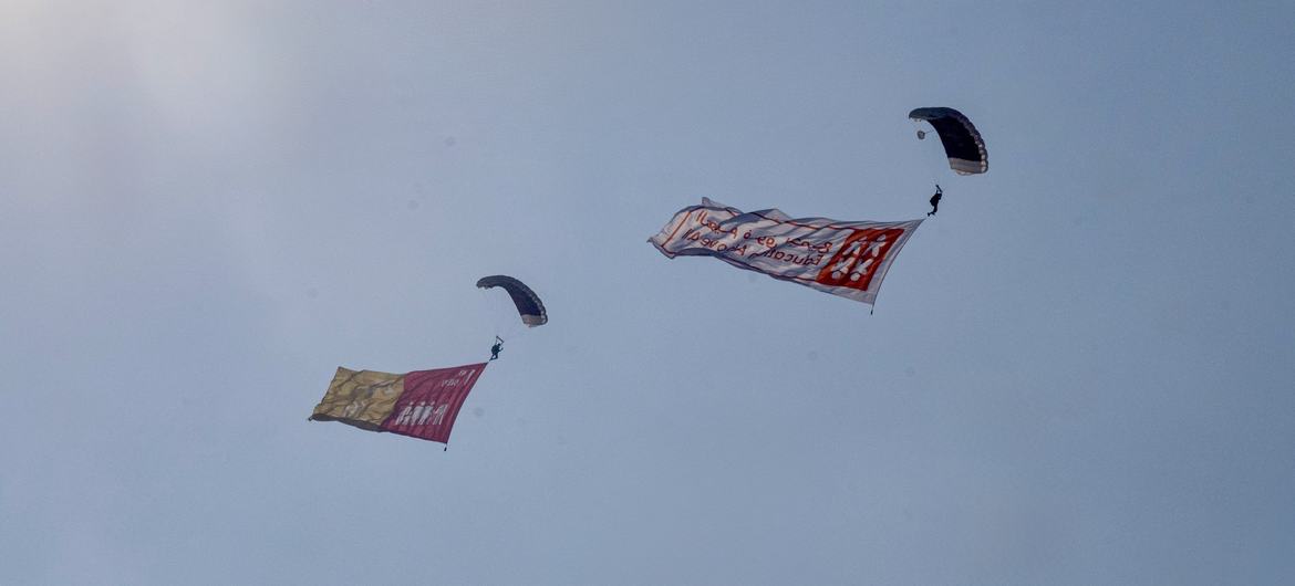 A team of parachutists descend over the QNCC, each carrying a flag representing one of the 17 Sustainable Development Goals.