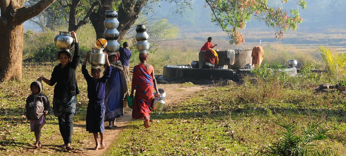 Women and children in a village fetch water from a well. Such chores keep children from attending classes and leaves women unable to engage in formal sectors.