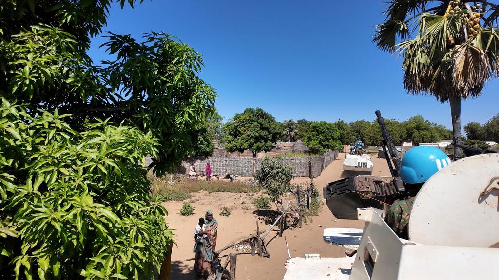 A UN peacekeeping vehicle patrols a flooded area in the Central African Republic, with MINUSCA forces navigating the terrain amid sparse infrastructure and local residents nearby.