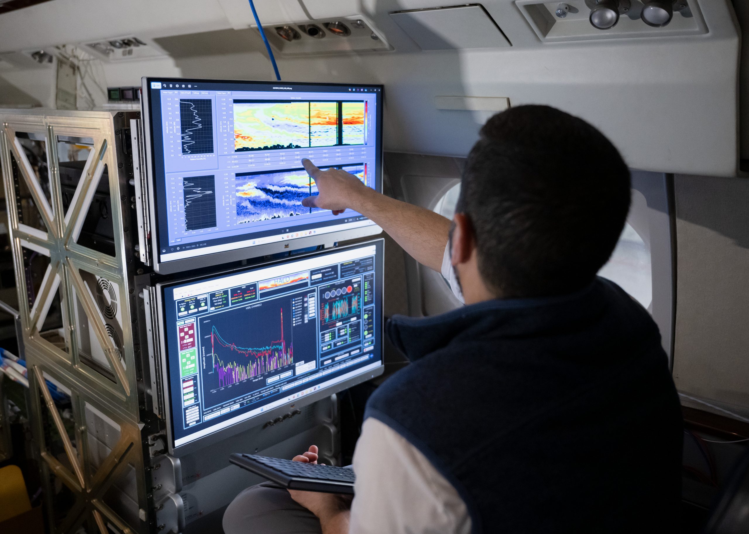 Two computer monitors are shown from the perspective of looking over a researcher's shoulder. The screens show colorful graphs representing smoke and aerosol measurements from previous missions with the HALO lidar instrument.