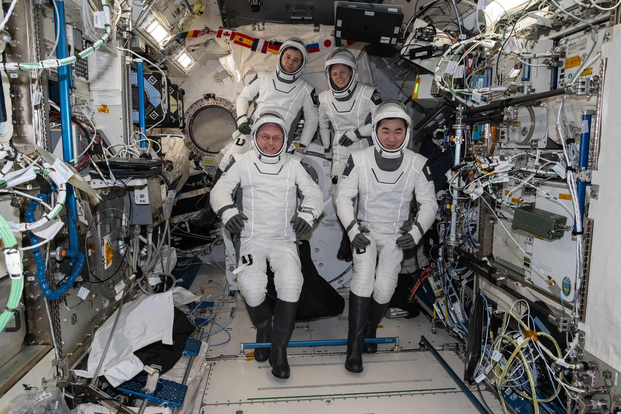 Four SpaceX Crew-11 members gather together for a crew portrait wearing their Dragon pressure suits during a suit verification check inside the International Space Station's Kibo laboratory module.