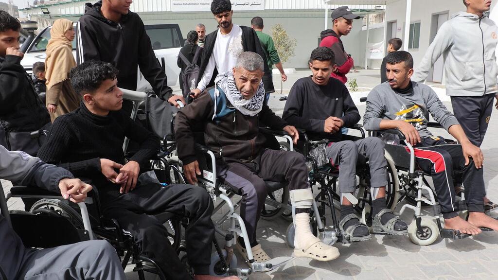 Patients, including some in wheelchairs, are being prepared for transport at Al-Amal Hospital in Gaza, affiliated with the Palestinian Red Crescent Society.
