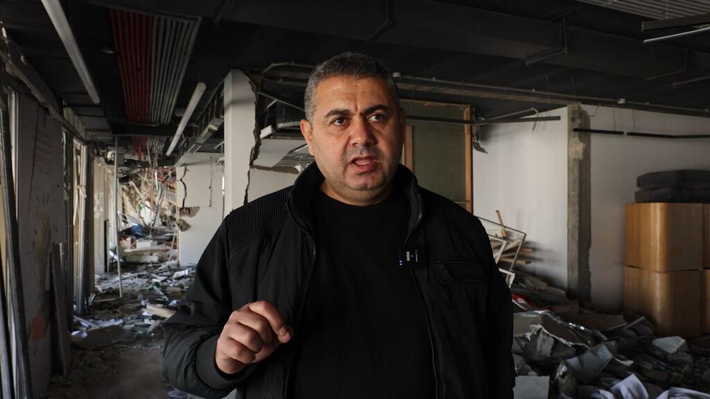 A man stands in a destroyed building in Gaza, surrounded by rubble and debris, speaking to the camera.