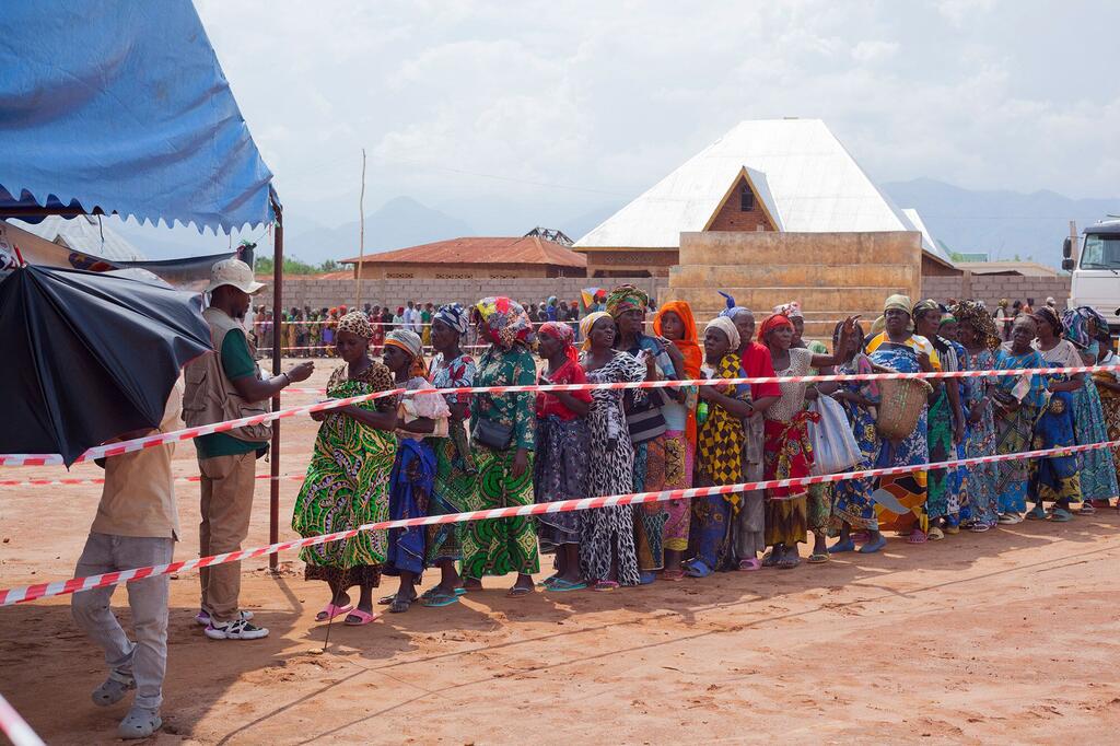 A line of displaced women in colorful attire waits for token verification to receive emergency food aid from WFP in Sange, Democratic Republic of Congo, on 19 December 2025.