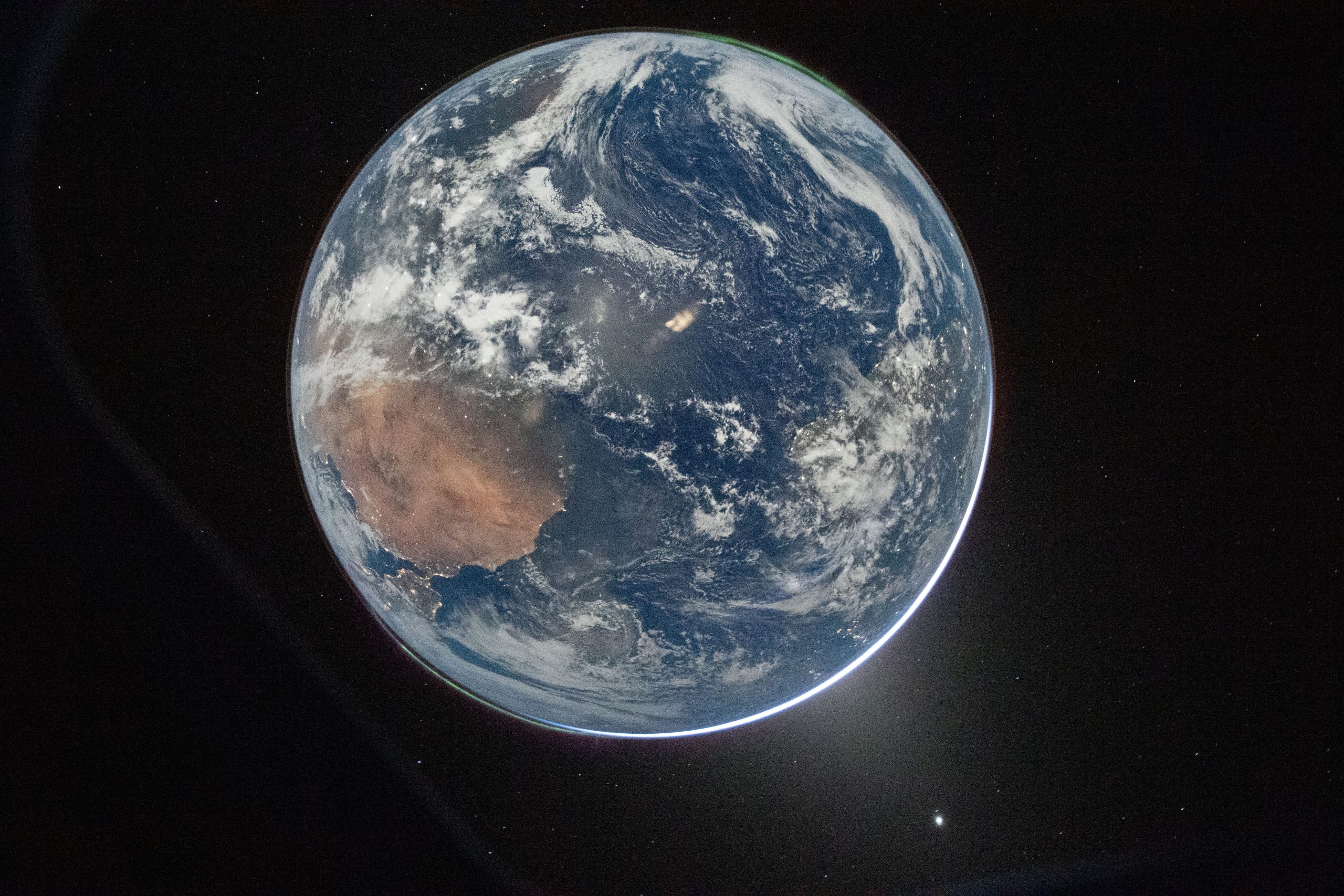 A view of Earth taken by NASA astronaut and Artemis II Commander Reid Wiseman from the Orion spacecraft's window. The image features two auroras (top right and bottom left) and zodiacal light (bottom right) is visible as the Earth eclipses the Sun.