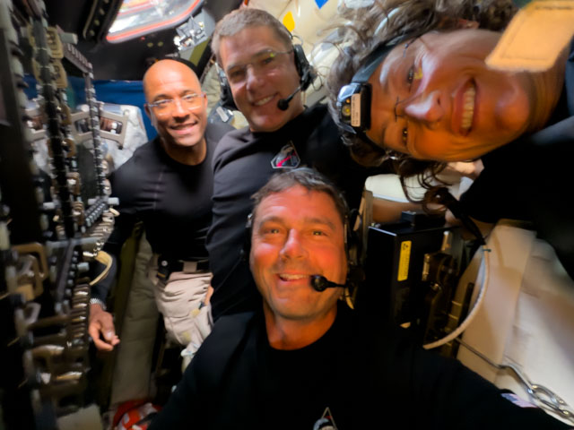 Midway through their lunar observation period on Monday, April 6, 2026, the Artemis II crew members, NASA astronauts Reid Wiseman, Victor Glover, Christina Koch, and CSA (Canadian Space Agency) astronaut Jeremy Hansen, pause to turn the camera around for a selfie inside the Orion spacecraft.