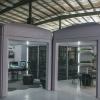 Two boxy structures, one with an office-like interior and the other with an eating area, side-by-side in a hangar-like location